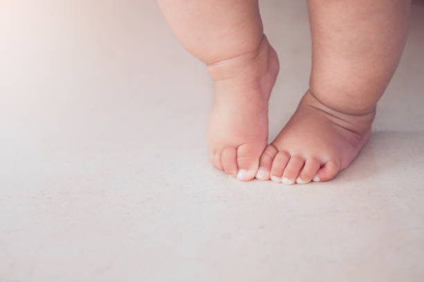 piccoli piedini che fanno il primo passo sul pavimento - steps baby standing walking foto e immagini stock