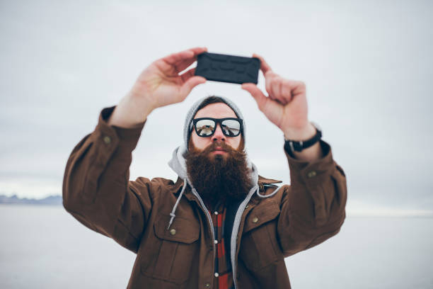 bearded hipster taking selfie in salt flats with retro tone with smart phone