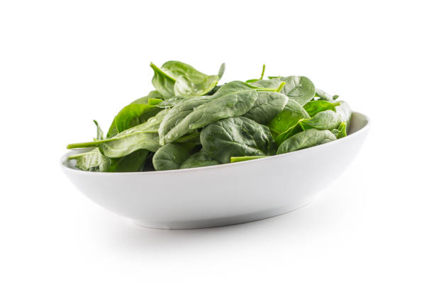 Spinach. Fresh baby spinach leaves in plate isolated on white.