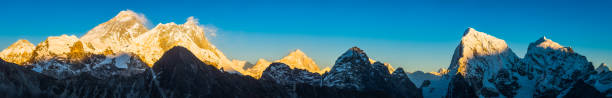 Golden sunset light illuminating the iconic pyramid peak of Mt. Everest (8848m) and the summits of Nuptse (7861m), Lhotse (8516m) and Makalu (8463m) in this vibrant Himalaya mountain panorama deep in the Sagarmatha National Park of Nepal, a UNESCO World Heritage Site.