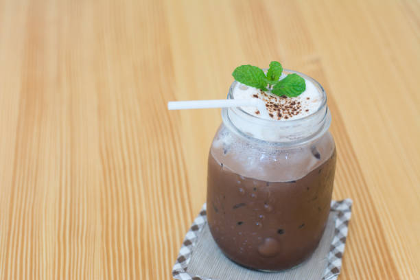 Chocolate smoothie (milkshake) with peppermint and straw in jar on wooden background