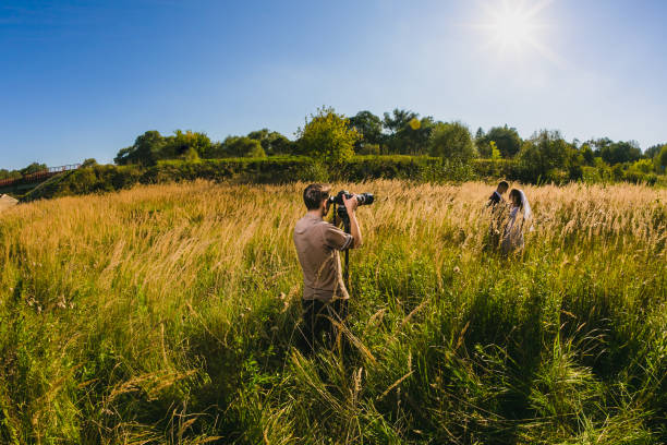 Photographer taking Pictures of the Bride and Groom in the summer park