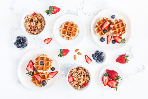 Waffles, kiwi and peanuts with curd cheese on a wooden table