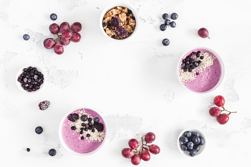 Breakfast with muesli, acai blueberry smoothie, fruits on white background. Healthy food concept. Flat lay, top view, copy space