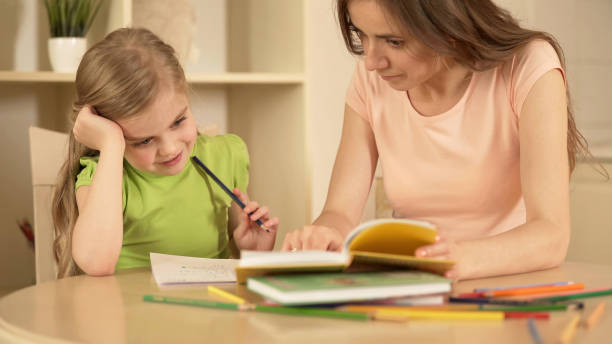 istock Mother helping daughter with homework, happy smart girl enjoying home education 930436708