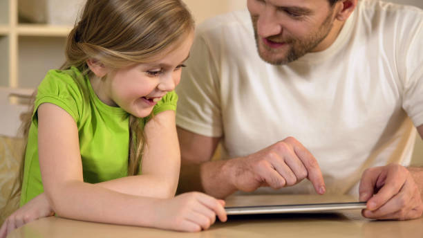 istock Happy father and daughter enjoying funny educational application on tablet pc 930437162