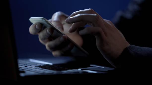 Scammer holds smartphone, cracks two-factor authentication, steals money online Scammer holds smartphone, cracks two-factor authentication, steals money online, stock footage computer hacker spy computer crime laptop stock pictures, royalty-free photos & images