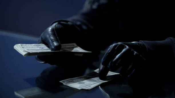 criminale in guanti neri conteggio pacchetto di soldi guadagnati per commettere reati - crime men bizarre kidnapper foto e immagini stock