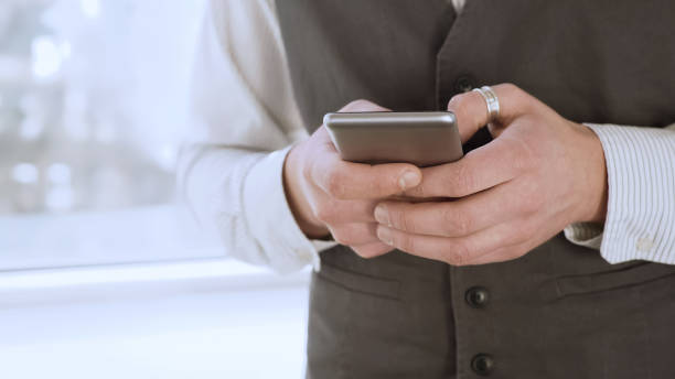 istock Male student standing by window and texting from smartphone, looking for job 930444180