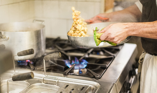 Hombre cocinero mezcla con pasta fresca salsa de cocina restaurante - barbado cocinero en el trabajo durante el servicio de cena - estilo italiano, estilo de vida y concepto de comida sana - centrarse en la mano photo