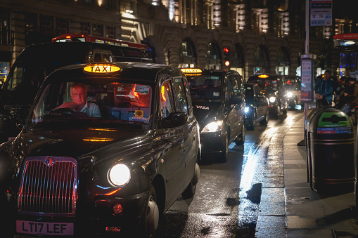 London, UK - March, 2018. A row of the iconic black cabs on Regent Street at night. Landscape format.