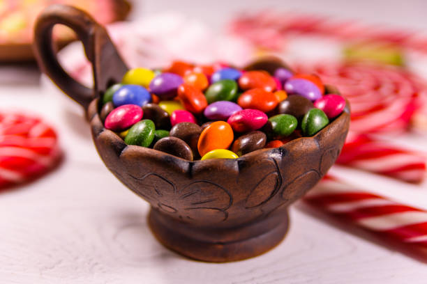 istock Ceramic bowl with colored candies, lollipops and marshmallows on a wooden table 930448166