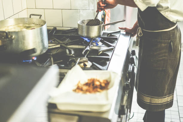 istock Male chef cooking in restaurant kitchen - Cook at work during dinner service - Italian style cuisine, lifestyle and healthy food concept - Focus on pot 930448234