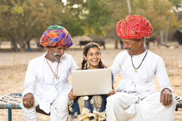 ländliche indische männer mit frau mit laptop - indian culture family senior adult asian ethnicity stock-fotos und bilder