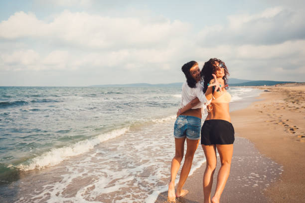 Woman and girl tourists enjoy vacation on beautiful Aegian sea rocky beach