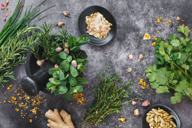 Fresh herbs and spices being ground up in mortar and pestle Fresh herbs and spices being ground up in mortar and pestle on dark background. Top view, blank space rosemary dry spice herbal medicine stock pictures, royalty-free photos & images