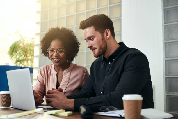 istock Smiling colleagues working online together at an office desk 930475882