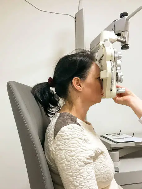 Woman undergoing an eye test at an optometrist testing the acuity of her eyes for the prescribing of corrective lenses for glasses