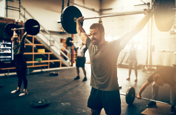 体育の授業でフィットの若い男ウエイト トレーニング - weight training crouching barbell weightlifting ストックフォトと画像