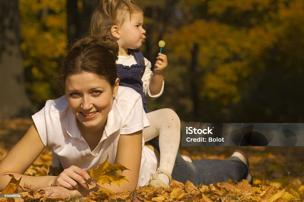 Madre e figlia gettare foglie cadendo giù su - Foto stock royalty-free di 20-24 anni