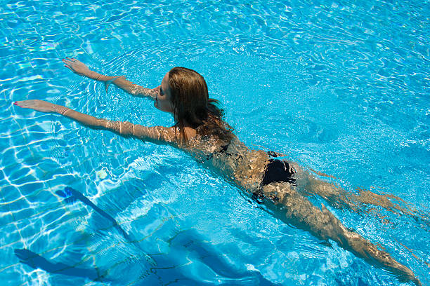 Happy young woman swimming in pool stock photo