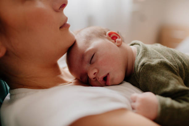 madre pone a su bebé - sleeping baby fotografías e imágenes de stock