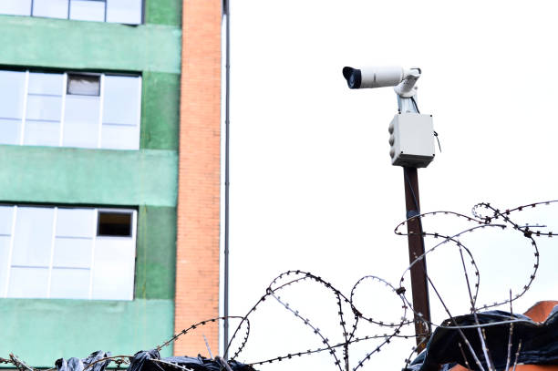 istock Camera video surveillance on the building background mounted on a brick wall, fenced with barbed wire. 930505200