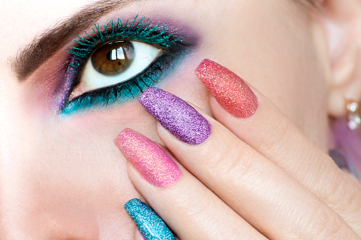 Colored makeup on brown eye and nail design.