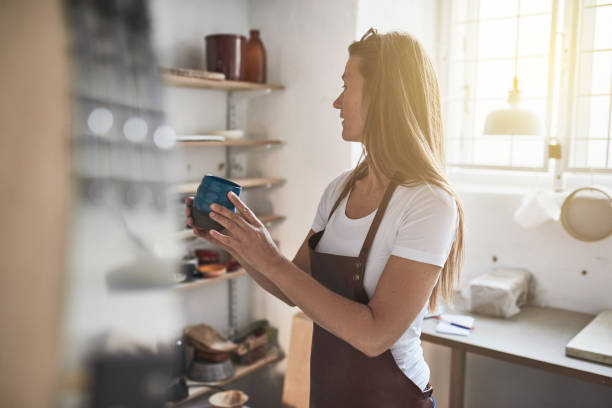 istock Female artisan holding glazed pottery in her creative workshop 930508116