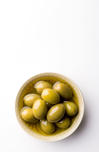Fresh olives in a bowl on a white background. Copy space. Top view