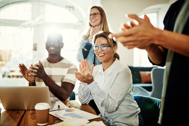 Diverse office colleagues smiling and clapping during an office meeting