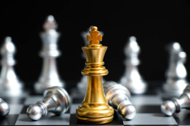 istock Gold King in chess game face with the another silver team on black background (Concept for company strategy, business victory or decision) 930523048