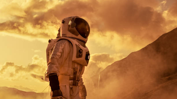 istock Courageous Astronaut in the Space Suit Explores Red Planet Mars Covered in Mist. Adventure. Space Travel, Habitable World and Colonization Concept. 930523120
