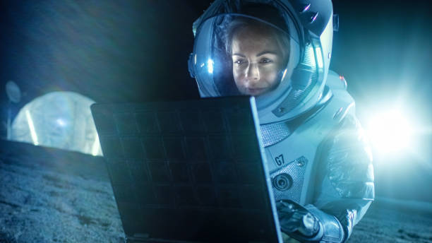 istock Female Astronaut Wearing Space Suit Works on a Laptop, Exploring Newly Discovered Planet, Communicating with the Earth. In the Background Space Habitat. Colonization Concept. 930523128