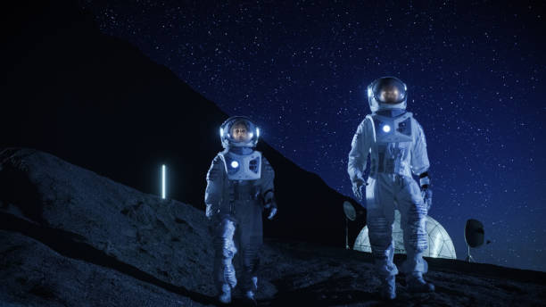 istock Two Astronauts in Space Suits Exploring Newly Discovered Planet. In the Background Space Base. Night Sky Full of Stars. Concept on Space Colonization. 930523148