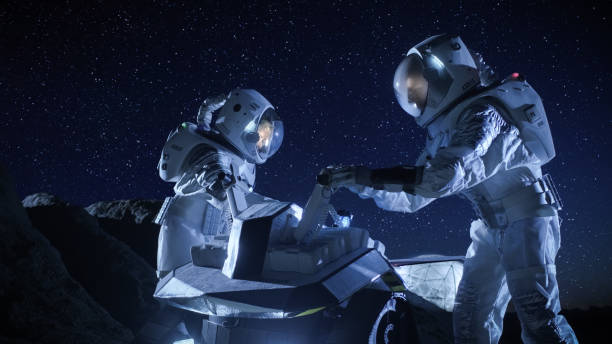 istock Two Astronauts in Space Suits on an Alien Planet Prepare Space Rover for Surface Exploration Mission. Futuristic Concept about Space Colonization. 930523172