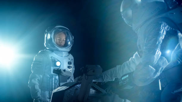 istock Two Astronauts in Space Suits on an Alien Planet Prepare Space Rover for Planet's Surface Exploration Expedition. Space Travel and Solar System Colonization Concept. 930523202