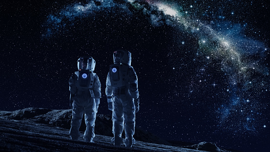 Tripulación de dos astronautas en trajes espaciales en la luna mirando la la Galaxia Vía Láctea. Concepto de alta tecnología de la colonización de la luna y viajes espaciales. photo