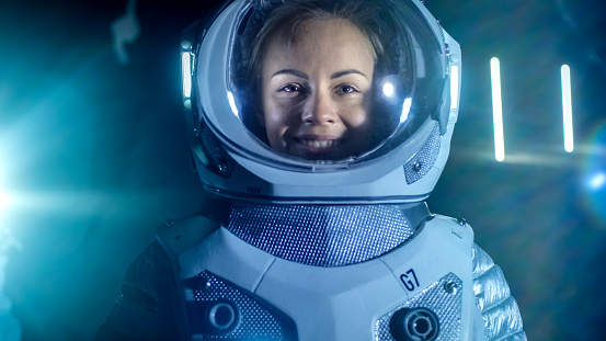 Portrait of the Beautiful Female Astronaut on the Alien Planet Looking around in Wonder, Smiles. In the Background Living Habitat. Space Travel, Exploration and Solar System Colonization Concept.