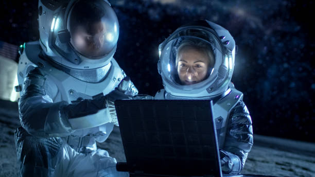 istock Two Astronauts Wearing Space Suits Work on a Laptop, Exploring Newly Discovered Planet, Communicating with the Earth. Space Travel, Exploration and Colonization Concept. 930523258