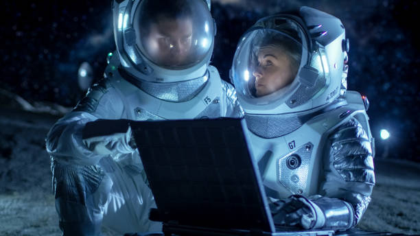istock Two Astronauts Wearing Space Suits Work on a Laptop, Exploring Newly Discovered Planet, Communicating with the Earth. Space Travel, Exploration and Colonization Concept. 930523274