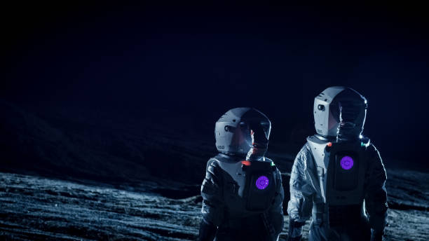 istock Two Astronauts in Space Suits on an Alien Planet Prepare Space Rover for Surface Exploration Mission. Futuristic Concept about Space Travel and Colonization. 930523354