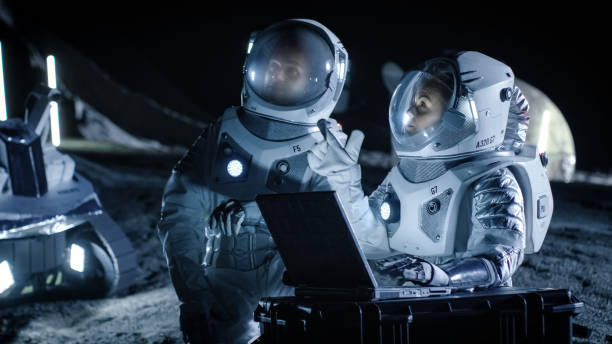 dois astronautas vestindo ternos de espaço de trabalho em um laptop, explorando o recém descoberto planeta, enviar comunicação de sinal para a terra. viagens espaciais, exploração interestelar e conceito de colonização. - colonization - fotografias e filmes do acervo