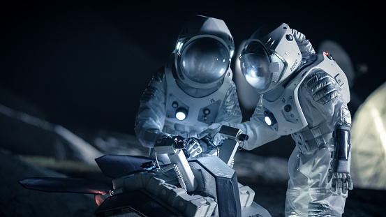 Two Astronauts in Space Suits on an Alien Planet Prepare Space Rover for Planet's Surface Exploration Expedition. Space Travel and Solar System Colonization Concept.