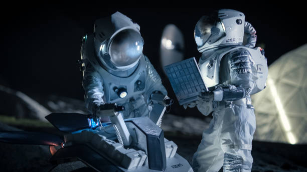 istock Two Astronauts in Space Suits on an Alien Planet Prepare Space Rover for Planet's Surface Exploration Expedition, Use Laptop. Space Travel and Solar System Colonization Concept. 930523406