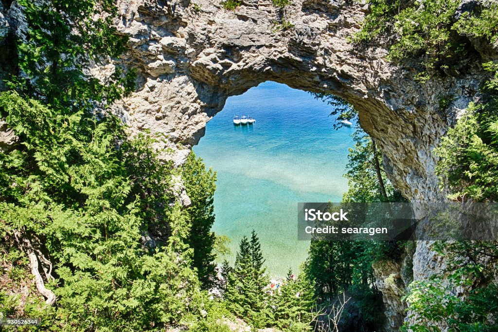 Arch Rock On Mackinac Island Three boats on Lake Huron are moored together underneath Arch Rock on Mackinac Island, Michigan. Mackinac Island Stock Photo