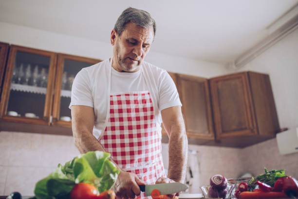 istock Senior man preparing salad in kitchen 930527430
