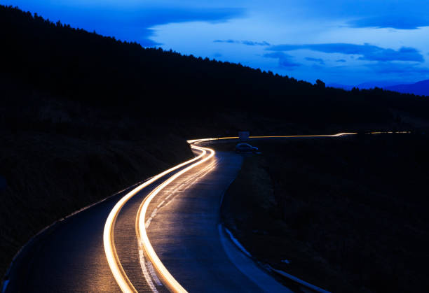 istock Car lights on mountain road at dusk 930527860