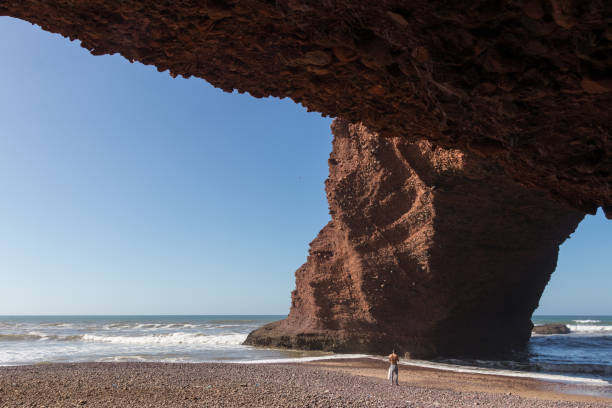 istock Young man looking at the stone arch from below 930530950