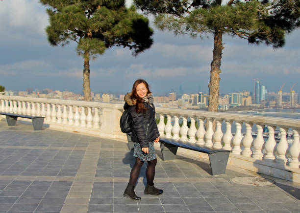 Traveling smile girl with a backpack in Baku, Azerbaijan. Girl walks around the Martyrs Lane viewpoint. Panorama on the Baku Boulevard baku national park stock pictures, royalty-free photos & images